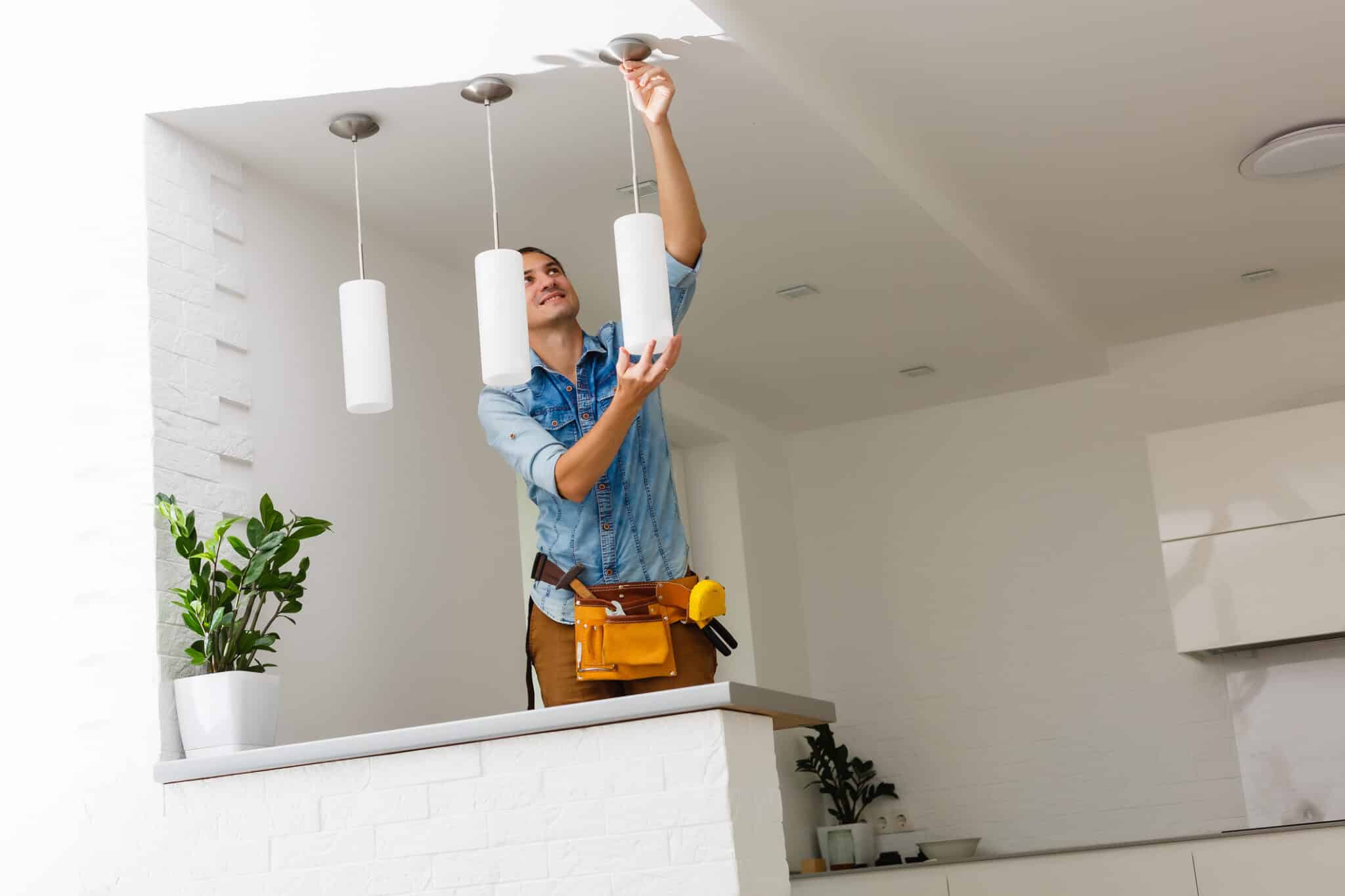 An electrician is performing a lighting installation by installing and connecting a ceiling lamp.
