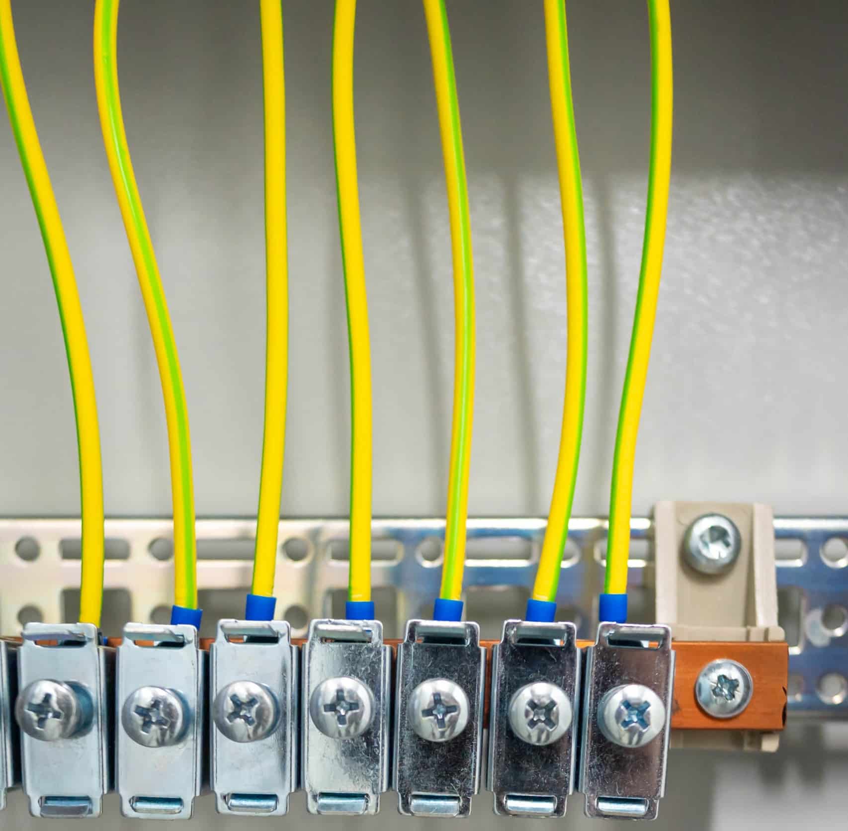 Grounding terminal block with connected yellow wires inside an industrial electrical panel, Bonding jumper sizing.
