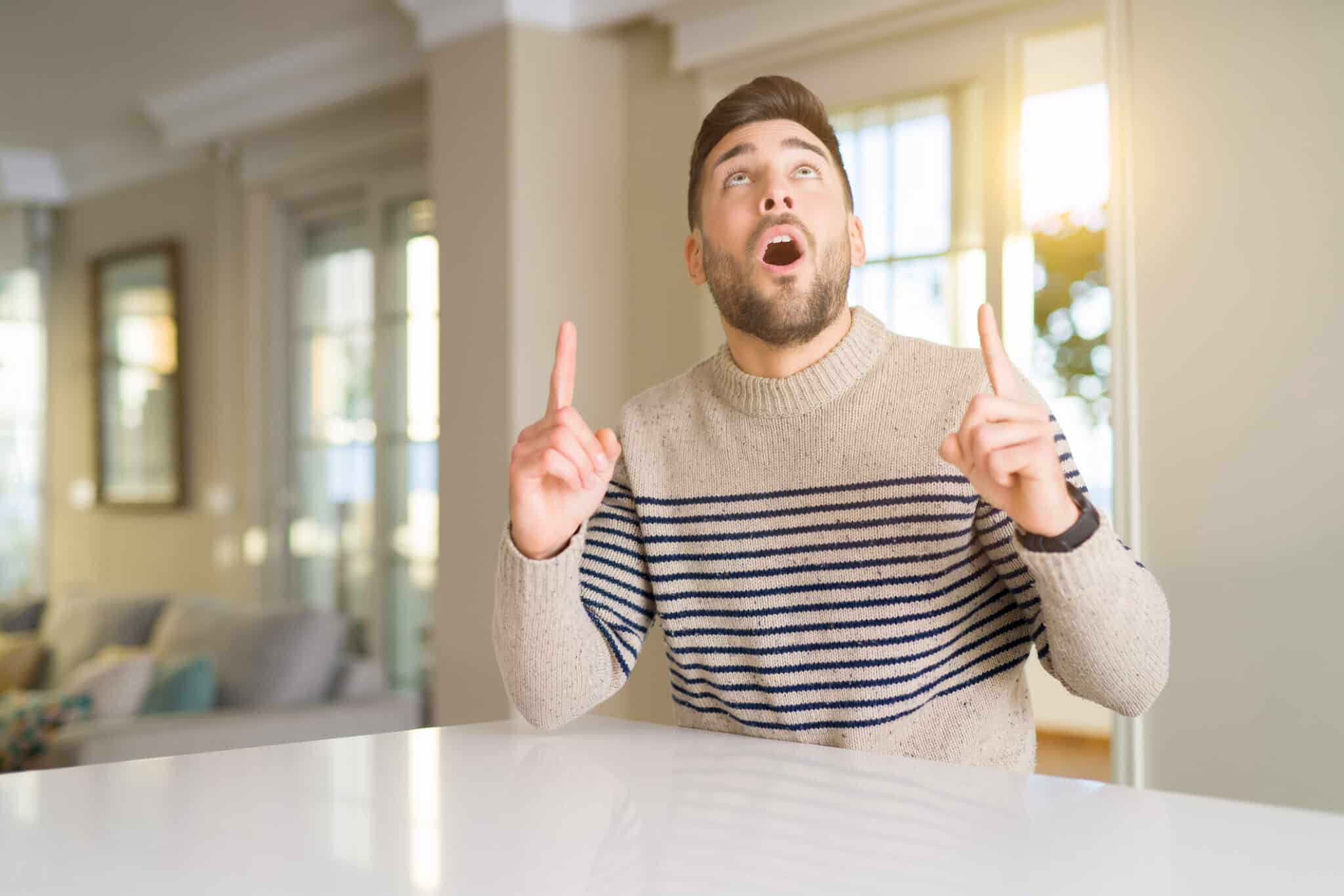 Young handsome man at home with fingers and raised arms, Ground rod testing.